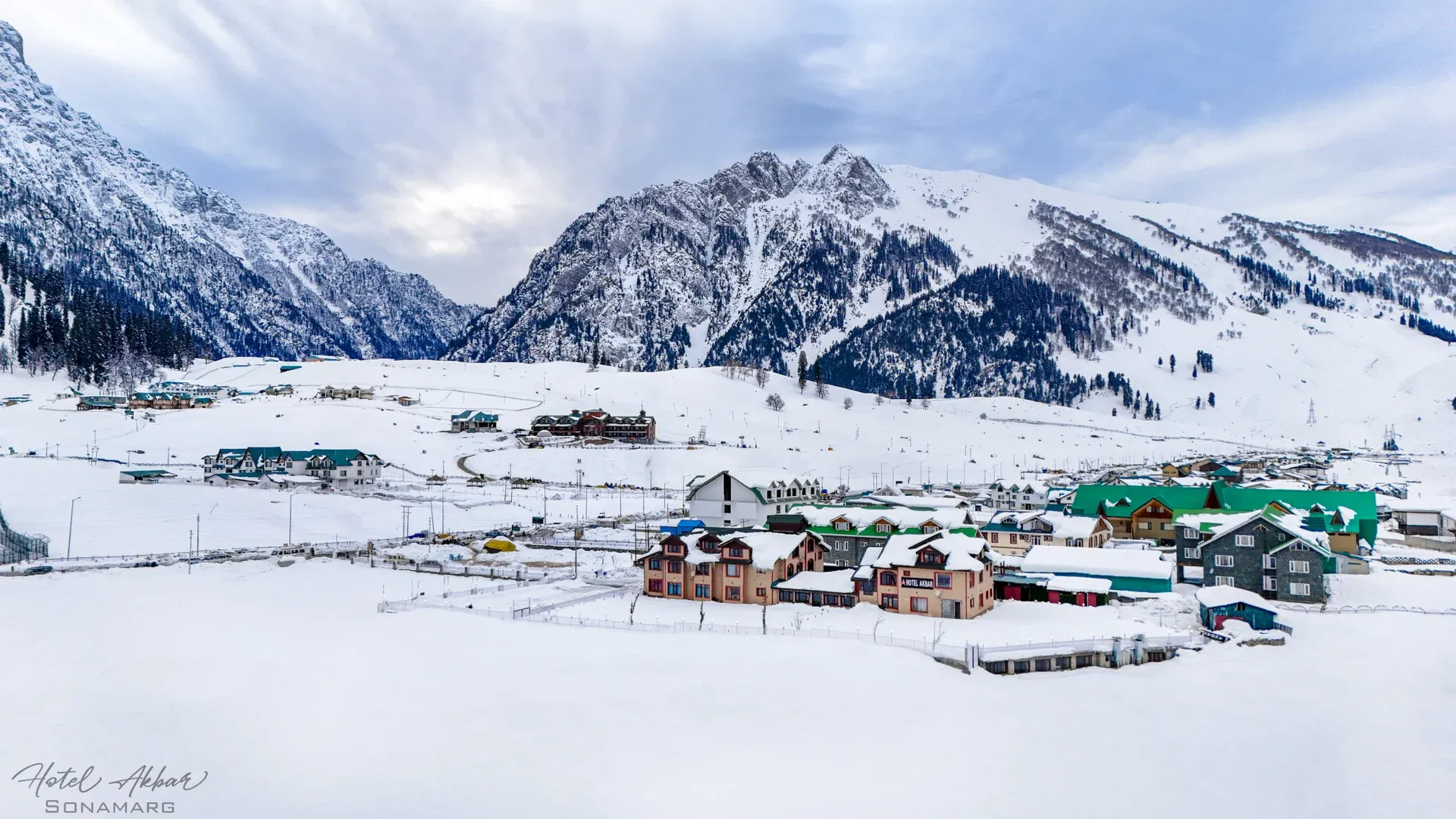 Snow-covered mountains surround village structures.